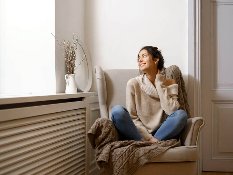 Mujer sonriente sentada en un sillón, en un ambiente relajado y acogedor