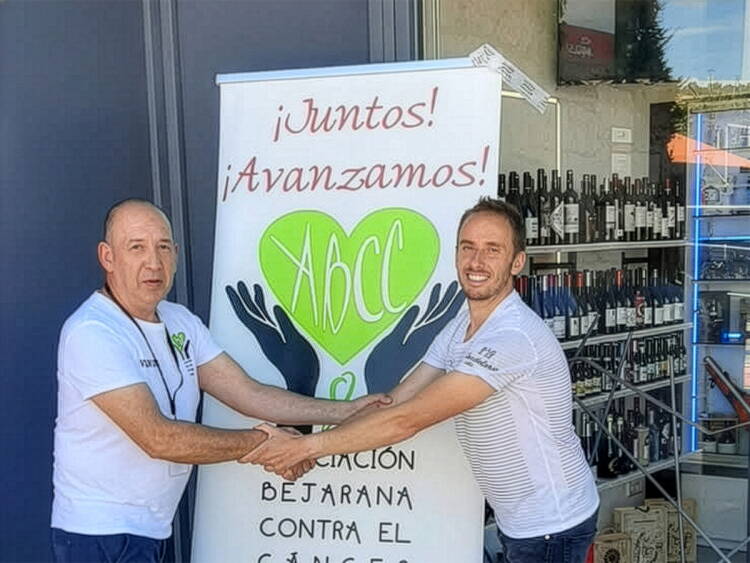 Eduardo Díaz y Elías Fraile estrechan sus manos junto al panel de la Asociación Bejarana Contra el Cáncer en Béjar