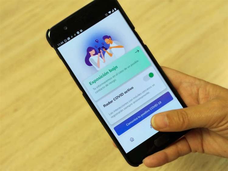 Mano sosteniendo un móvil con la aplicación Radar Covid abierta
