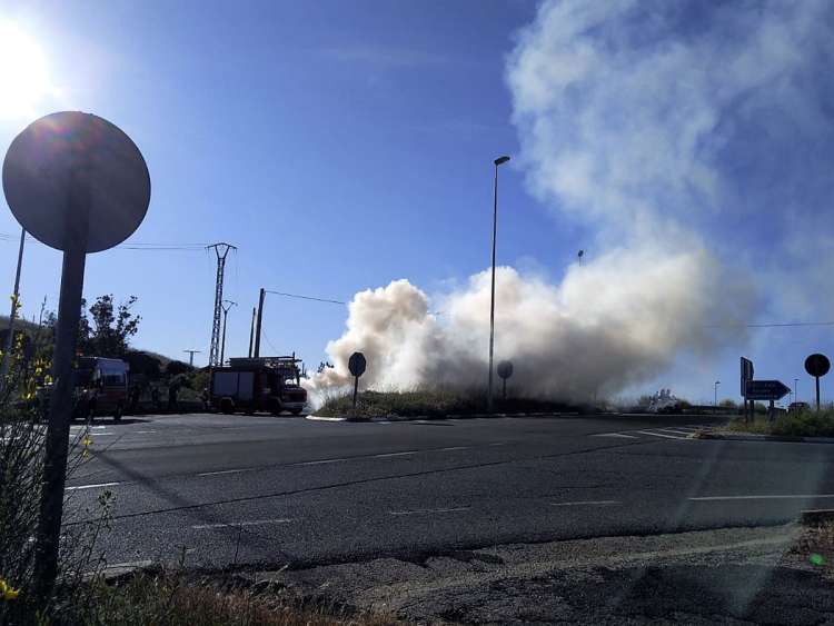 Humo blanco saliendo del coche incendiado. Junto al coche varias dotaciones de bomberos