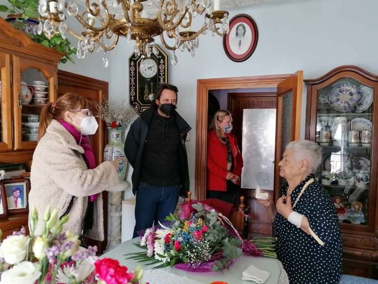 Cuatro personas en el interior de una casa, con un ramo de flores sobre la mesa