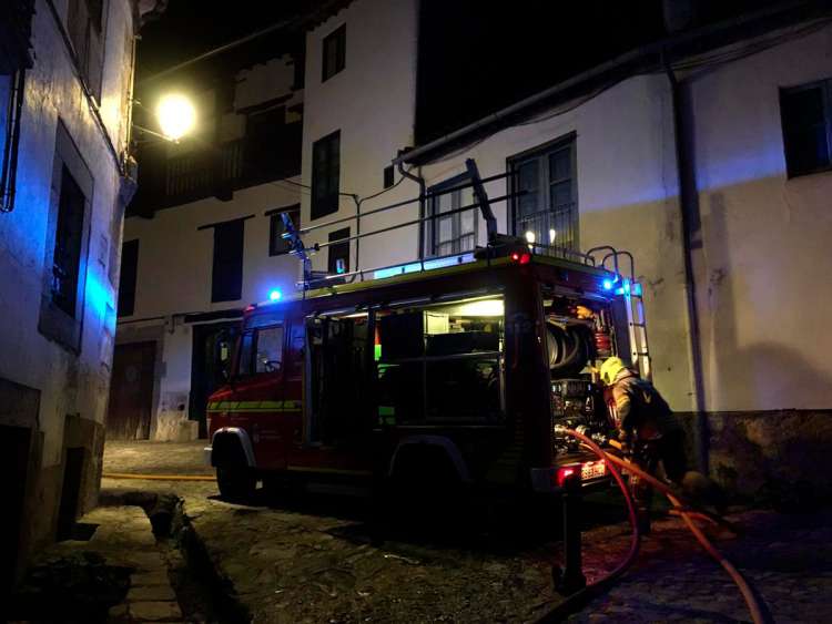 Camión de bomberos y varios bomberos en una calle 
