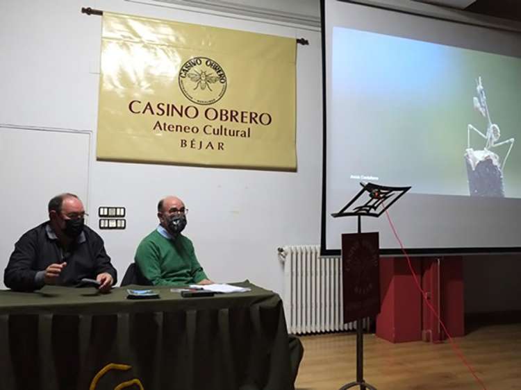 Dos personas sentadas a una mesa con una proyección