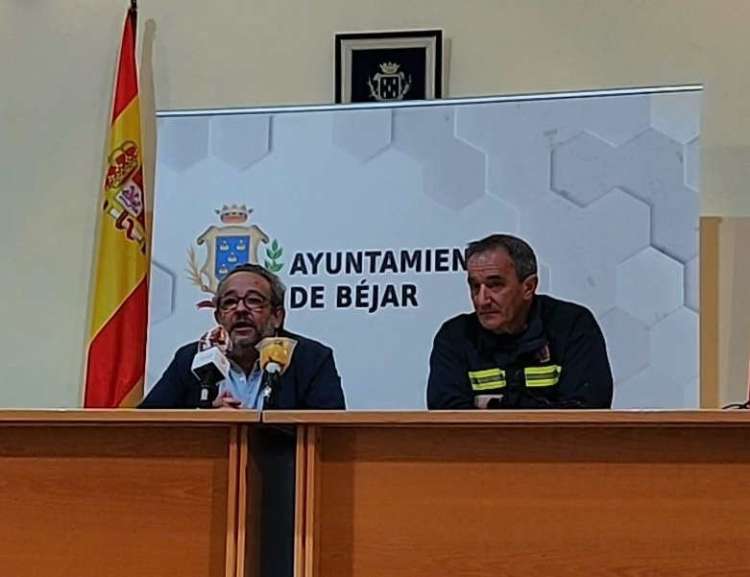 Dos personas sentadas en una mesa con microfonos