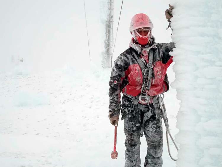 Operario de mantenimiento junto a pilona llena de nieve