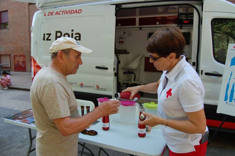 Voluntaria de Cruz Roja ofrece agua a un vecino en una actividad de sensibilización contra el calor