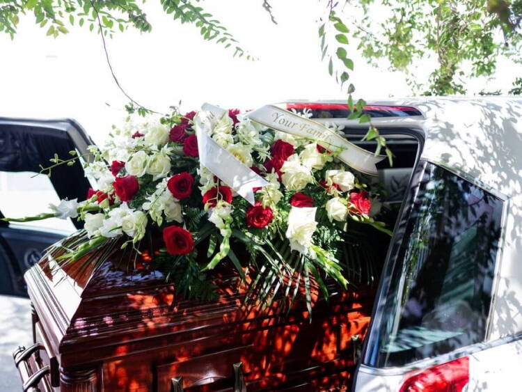 Féretro cubierto de flores metido en un coche