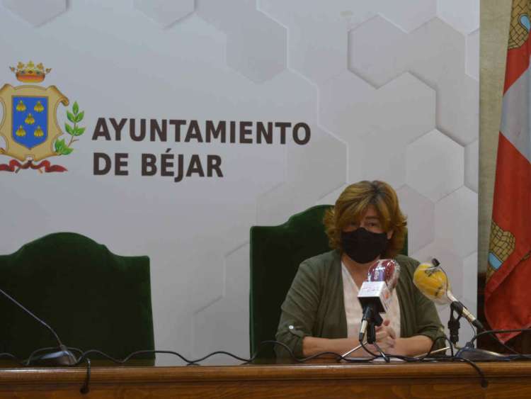 Mujer sentada en una mesa con escudo de Béjar detrás