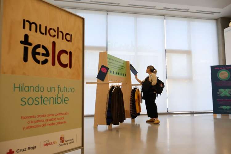 Mujer observa panel educativo sobre sostenibilidad textil en la exposición de Cruz Roja