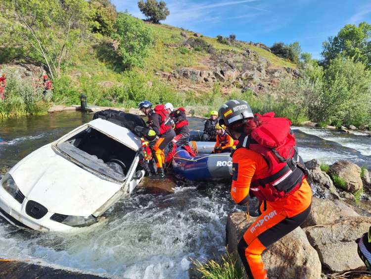 Varios profesionales trabajan sobre un vehículo que ha caído al rio