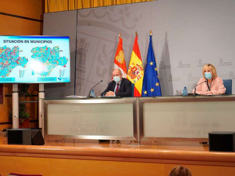 Dos personas sentadas tras una mesa con pantalla de TV a la izquierda