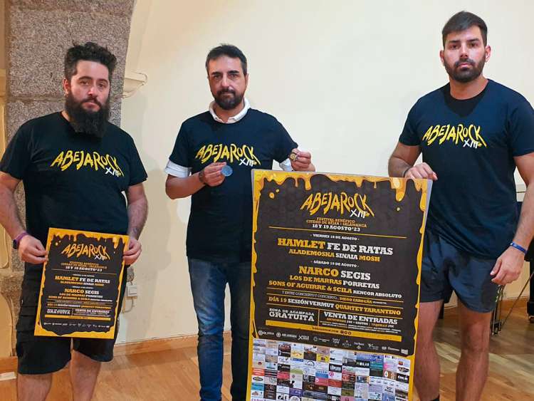 Tres personas sosteniendo carteles del AbejaRock