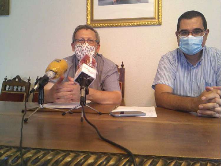 Dos hombres sentados a una mesa con microfonos