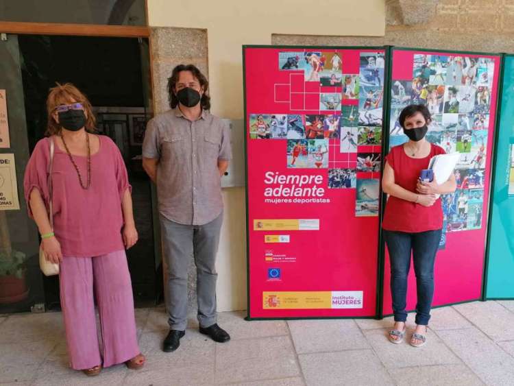 tres personas junto a varios carteles de la exposición