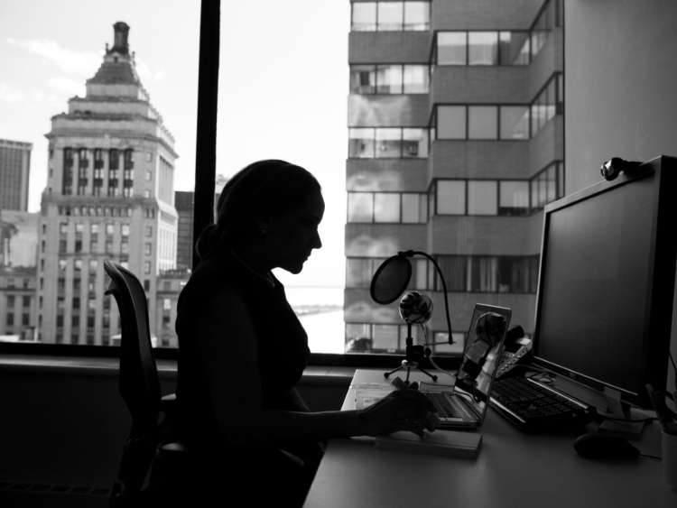 Mujer sentado al ordenador con ventana al fondo