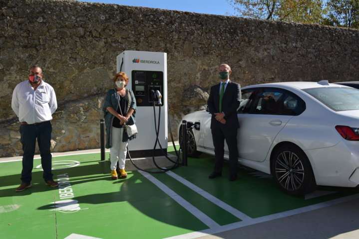 Punto de carga rápida, responsables municipales y de Iberdrola junto a un coche cargando