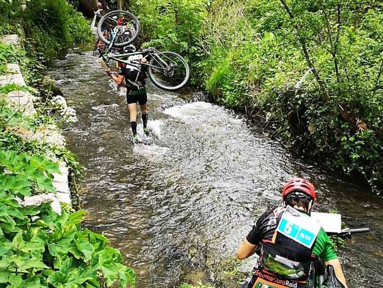 Dos raiders con sus bicicletas por un río
