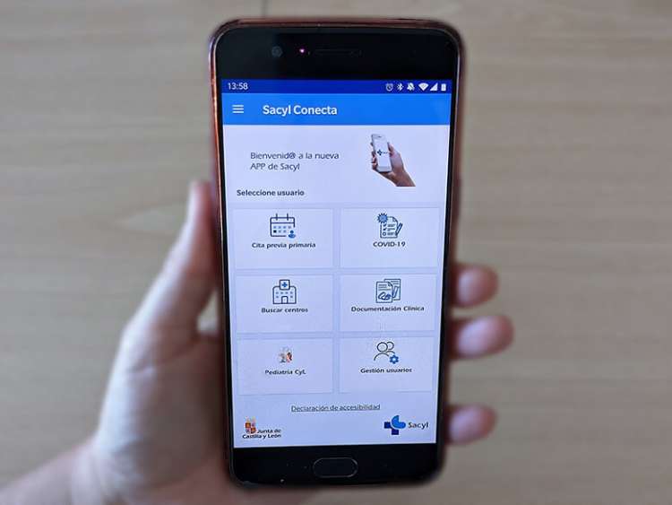 Mano sosteniendo móvil con la aplicación Sacyl Conecta en pantalla