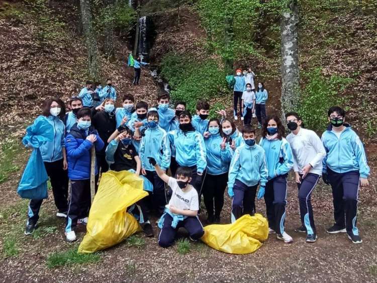 Una veintena de niños con bolsas con la basura recogida, en el bosque