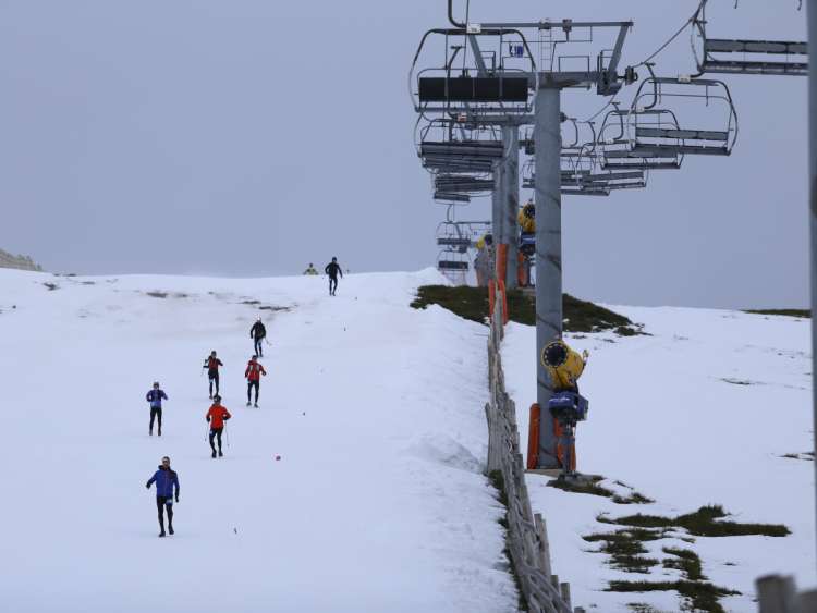 Varios corredores bajando por una pista de nueve junto al telesilla