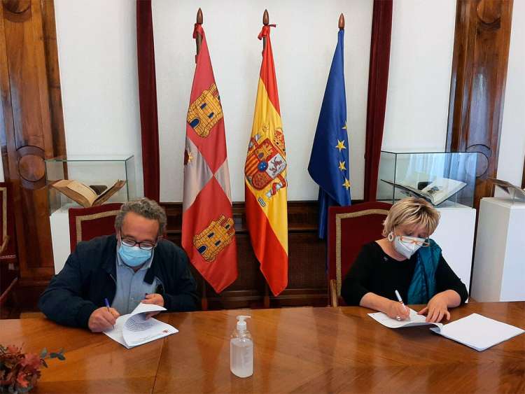 Dos personas firmando un documento sentados en una mesa