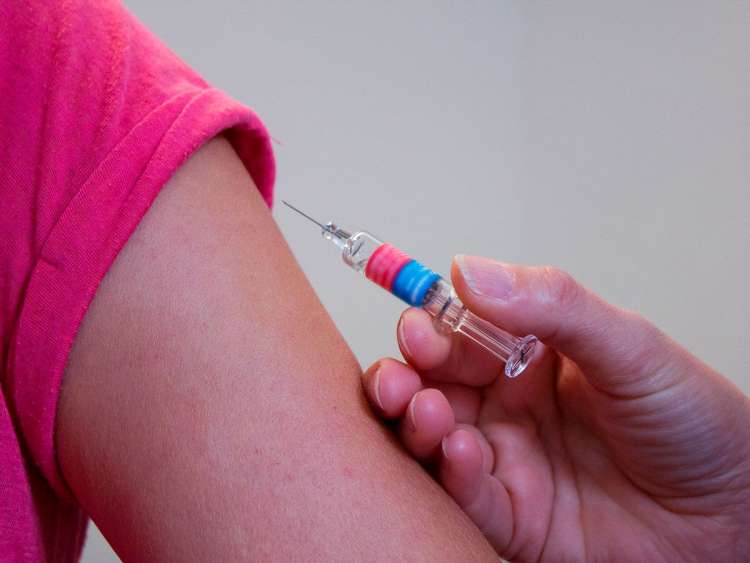 Brazo de una persona y mano con vacuna inyectable