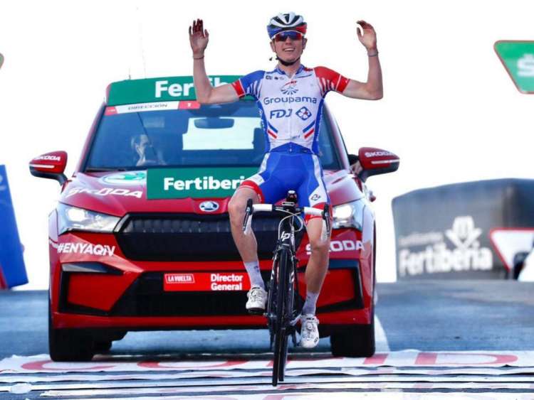Ciclista con brazos en alto con coche detrás