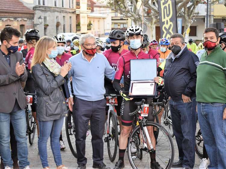 Varias personas junto a un ciclista con placa en las manos