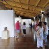 Grupo de personas en la sala principal de la exposición "Femenino Plural" en Béjar, rodeadas de obras de arte