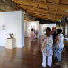 Visitantes conversan junto a obras pictóricas en la exposición "Femenino Plural" celebrada en Béjar