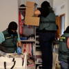 gentes de la Guardia Civil inspeccionan un domicilio durante la operación contra una red de estafas por vishing