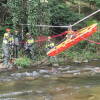 Varios bomberos en la orilla del rio transportando una camilla sobre el rio
