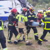 Varios bomberos portean a un herido en camilla