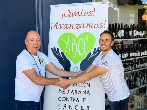 Eduardo Díaz y Elías Fraile estrechan sus manos junto al panel de la Asociación Bejarana Contra el Cáncer en Béjar