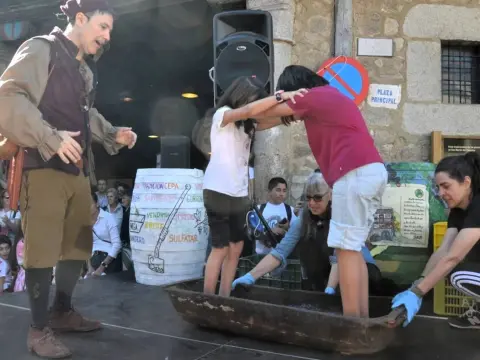 Varias personas pisan uvas durante la Fiesta de la Vendimia en San Martín del Castañar