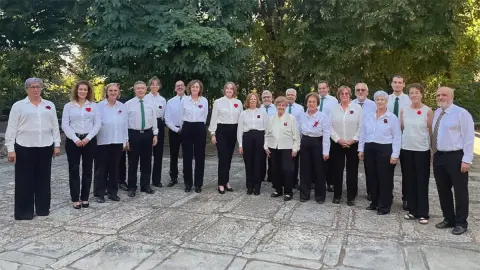 Miembros de la Coral de Béjar con estolas verdes delante de un altar barroco