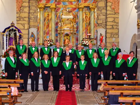 Miembros de la Coral de Béjar con estolas verdes delante de un altar barroco