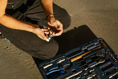 Persona agachada con caja de herramientas a los pies
