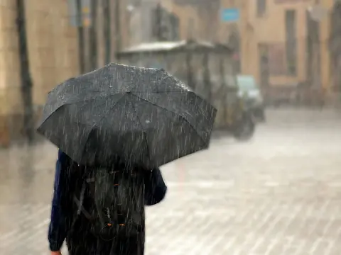 Persona con paraguas paseando bajo una intensa lluvia