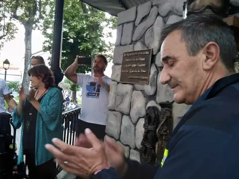 Varias personas aplaudiendo con una placa conmemorativa de fondo