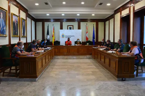 Varias personas sentadas alrededor de una mesa en forma de U