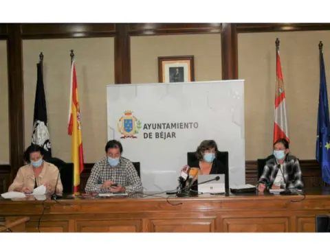 Cuatro personas con mascarilla sentadas a una mesa